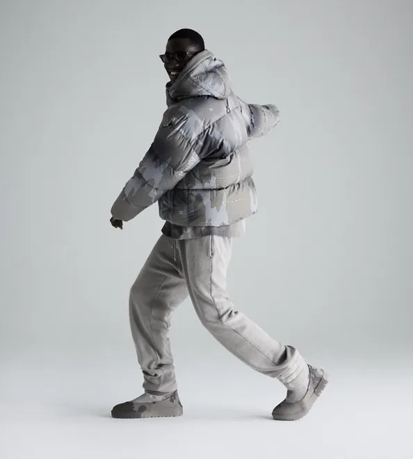 A person posing standing wearing the UGG Stampd collection on a neutral background.