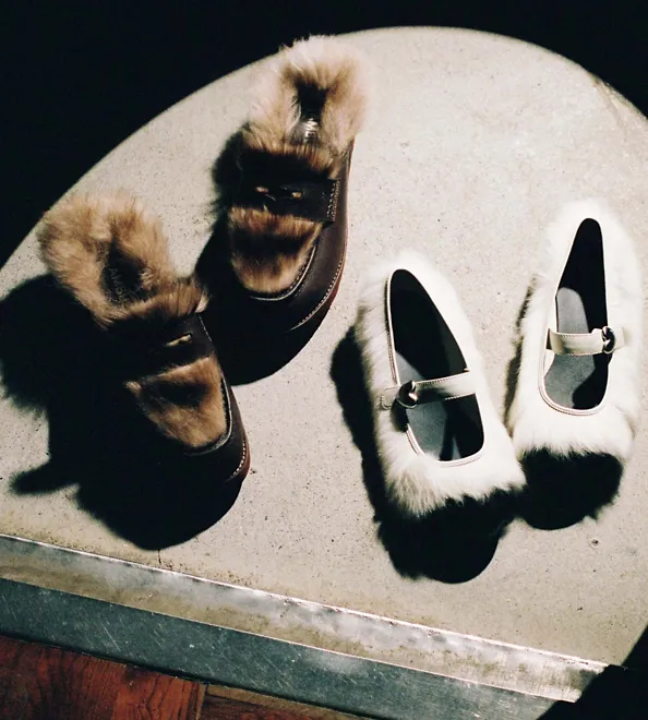 Pairs of UGG Ambush collab shoes lying on the floor being focused by a beam of light.