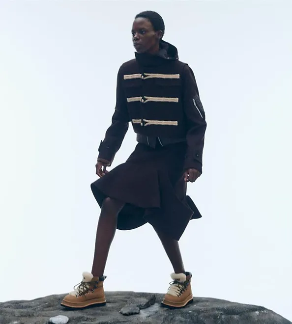 A man stands on a rock in a cold-weather outfit and the UGG sacai Hiker.