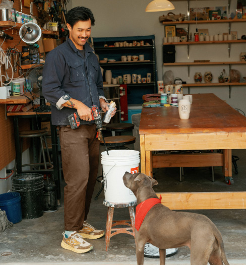 Man wearing Clifton L Suede standing near a dog.