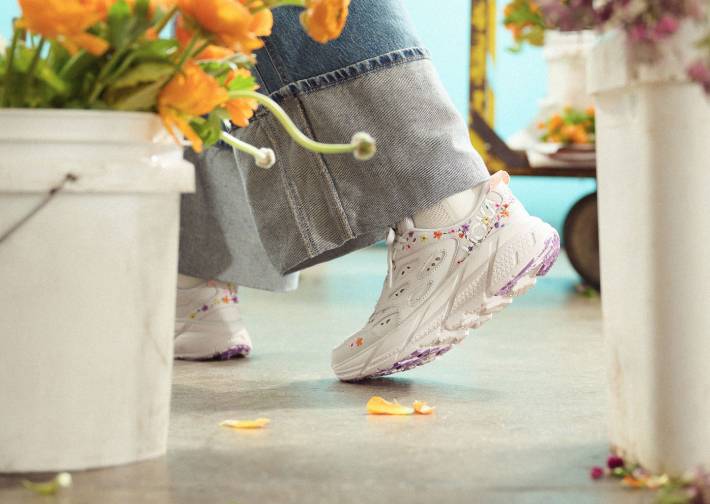 Focus on a person legs taking a step and wearing HOKA Vibrant Bloom Clifton L shoes.