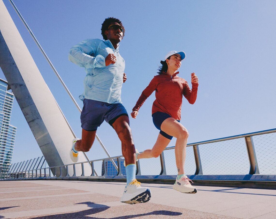 Deux personnes courant en portant des vêtements HOKA.