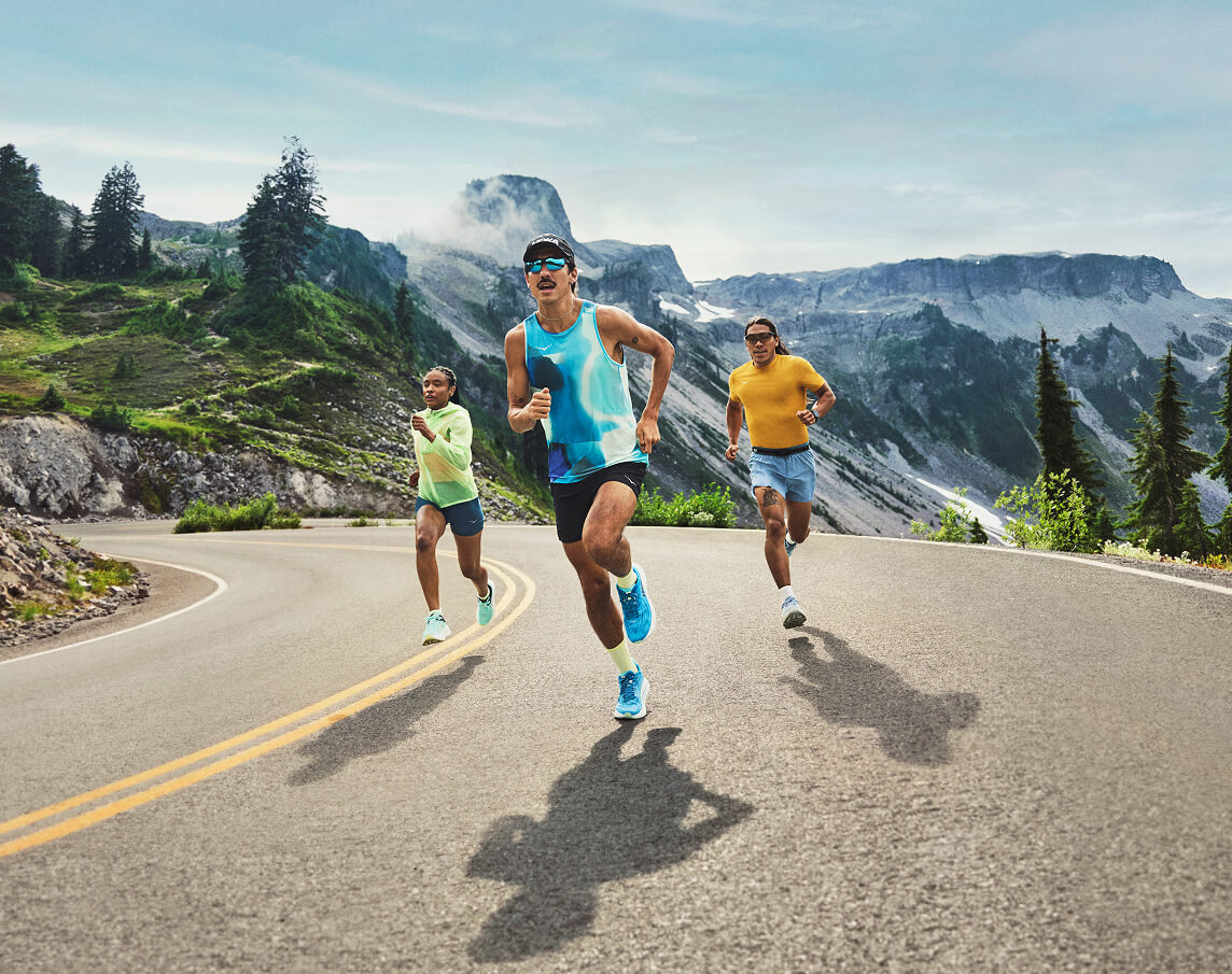 Trois personnes courant sur une route de montagne portant des équipements HOKA et des chaussures de course sur route HOKA.