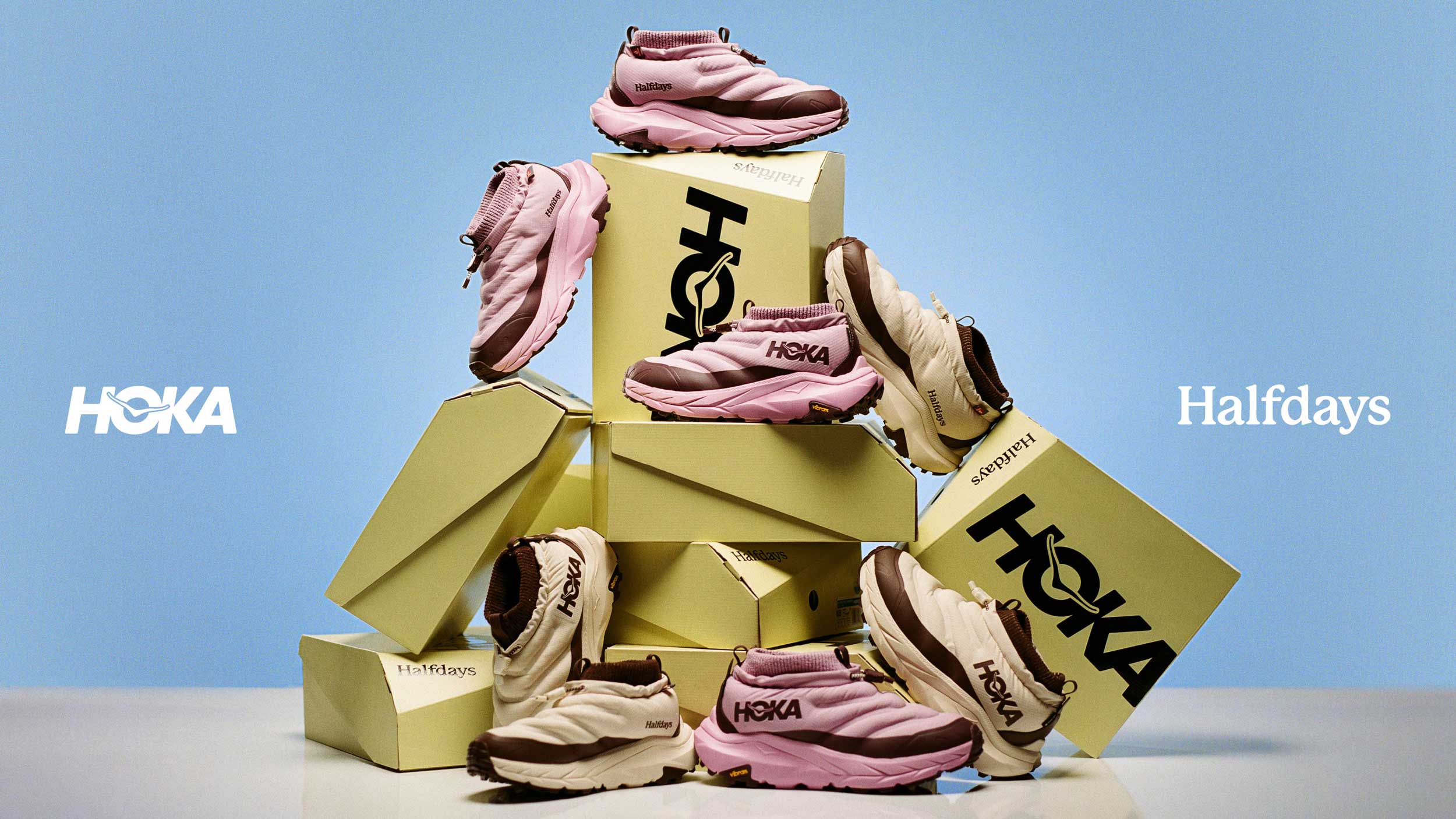 Chaussures de collaboration HOKA Kaha 2 Frost GTX Halfdays posées sur des boîtes à chaussures HOKA empilées.