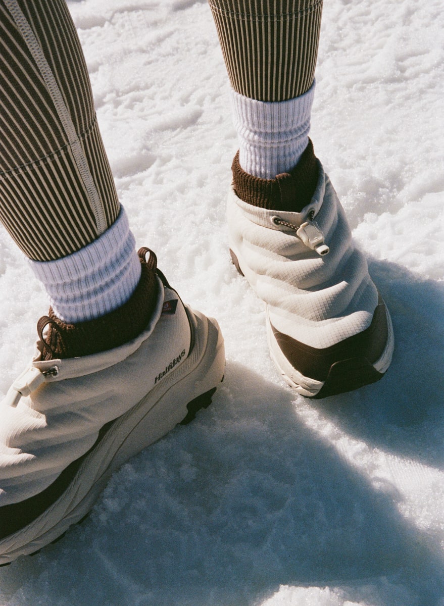 Gros plan des pieds d’une personne marchant sur la neige et portant des chaussures HOKA Kaha 2 Frost Moc GTX Halfdays.