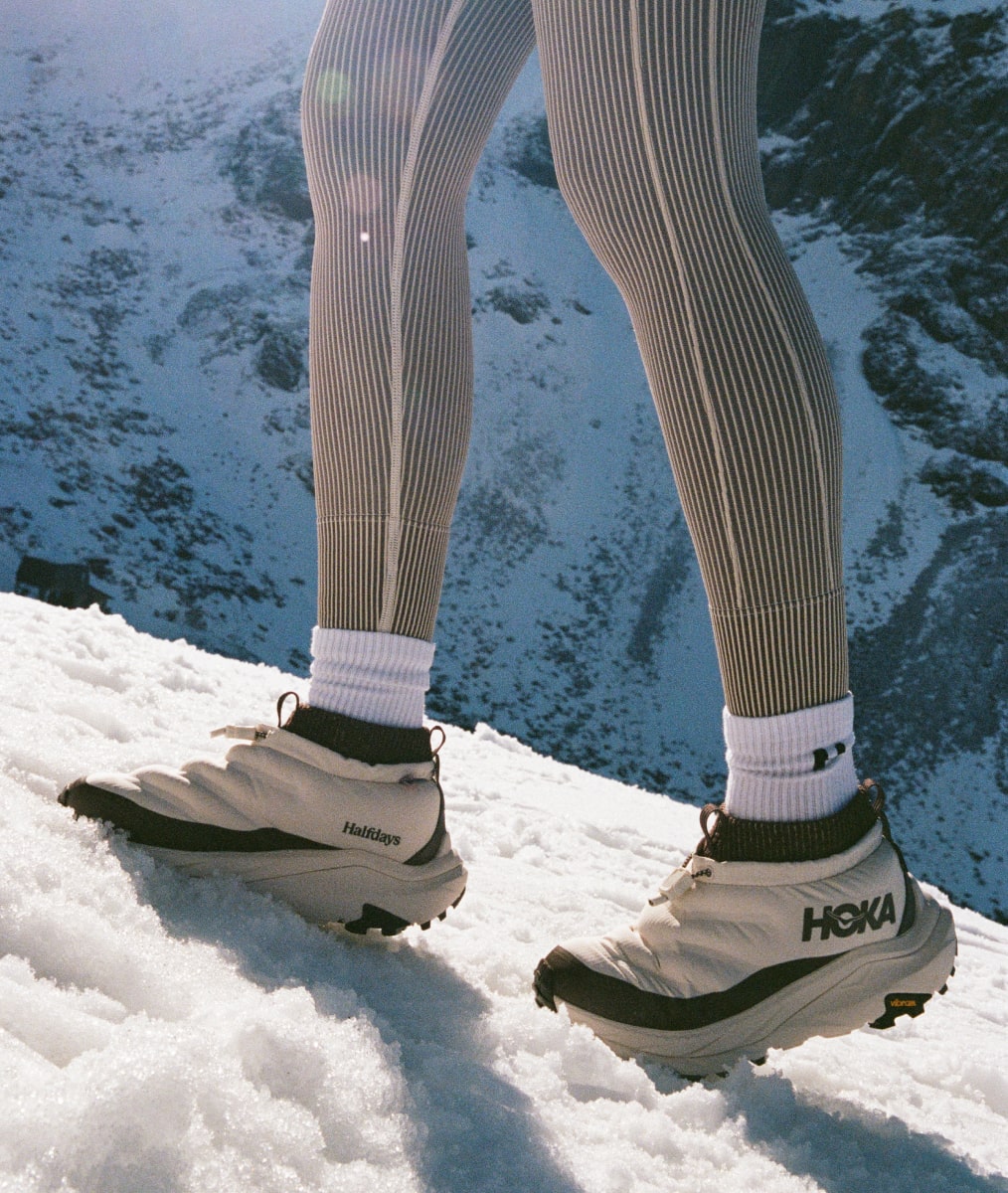 Gros plan des jambes d’une personne marchant sur la neige et portant des chaussures HOKA Kaha 2 Frost Moc GTX Halfdays.