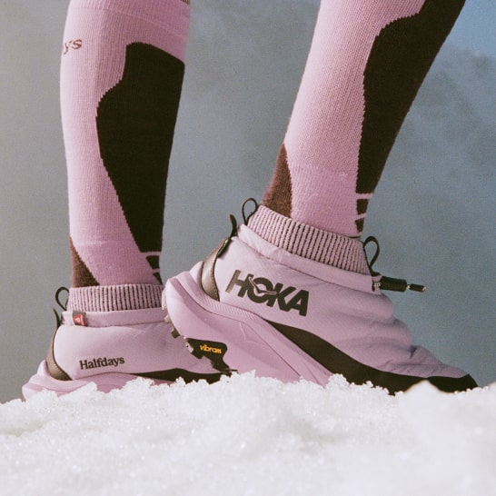 Gros plan des pieds d’une personne debout dans la neige et portant des chaussures HOKA Kaha 2 Frost Moc GTX Halfdays.