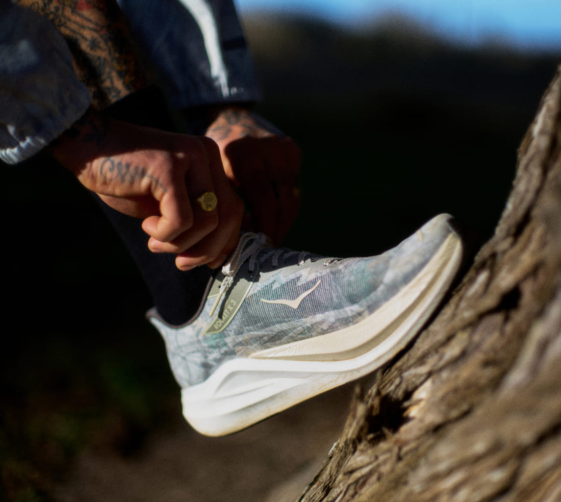 Photo de John Elliott en train de nouer ses chaussures HOKA.