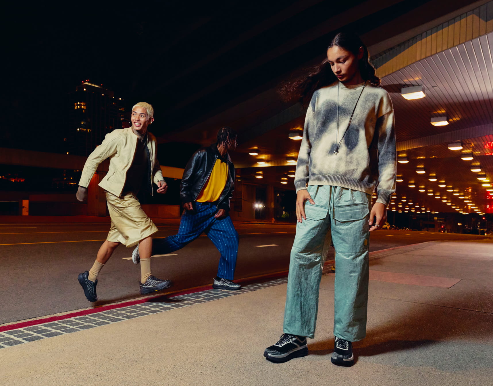 Une personne debout et deux marchant, toutes portant des chaussures HOKA.