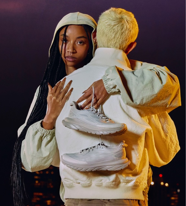 Deux personnes s’embrassant, l’une tenant des chaussures HOKA.