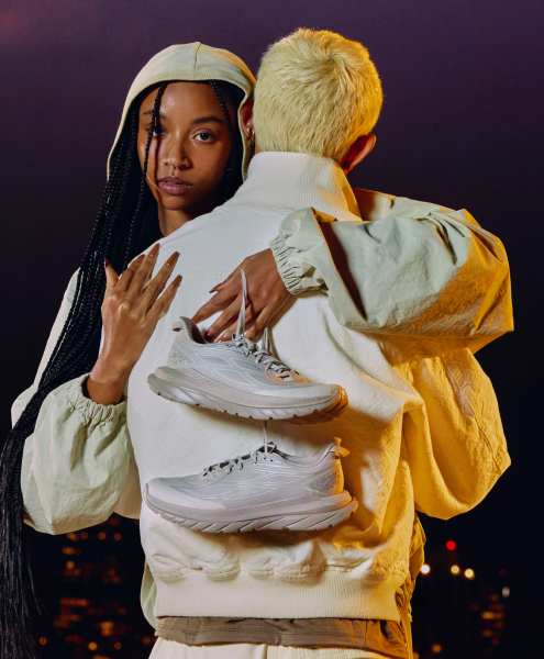 Deux personnes s’embrassant, l’une tenant des chaussures HOKA.