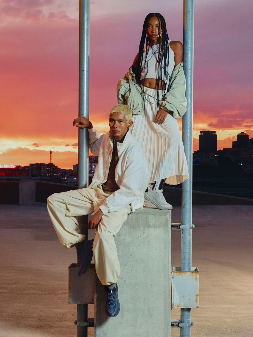 Trois personnes modélisant Mach Remastered avec la silhouette d’une ville au coucher de soleil en arrière-plan.