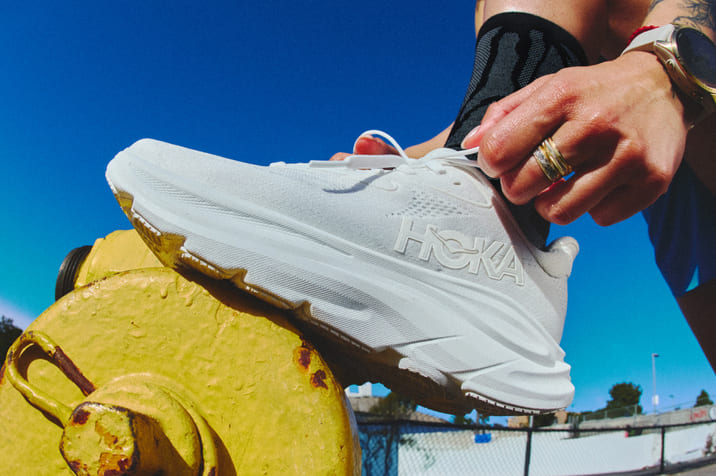 Gros plan d’une personne en train de nouer les lacets de sa chaussure HOKA.