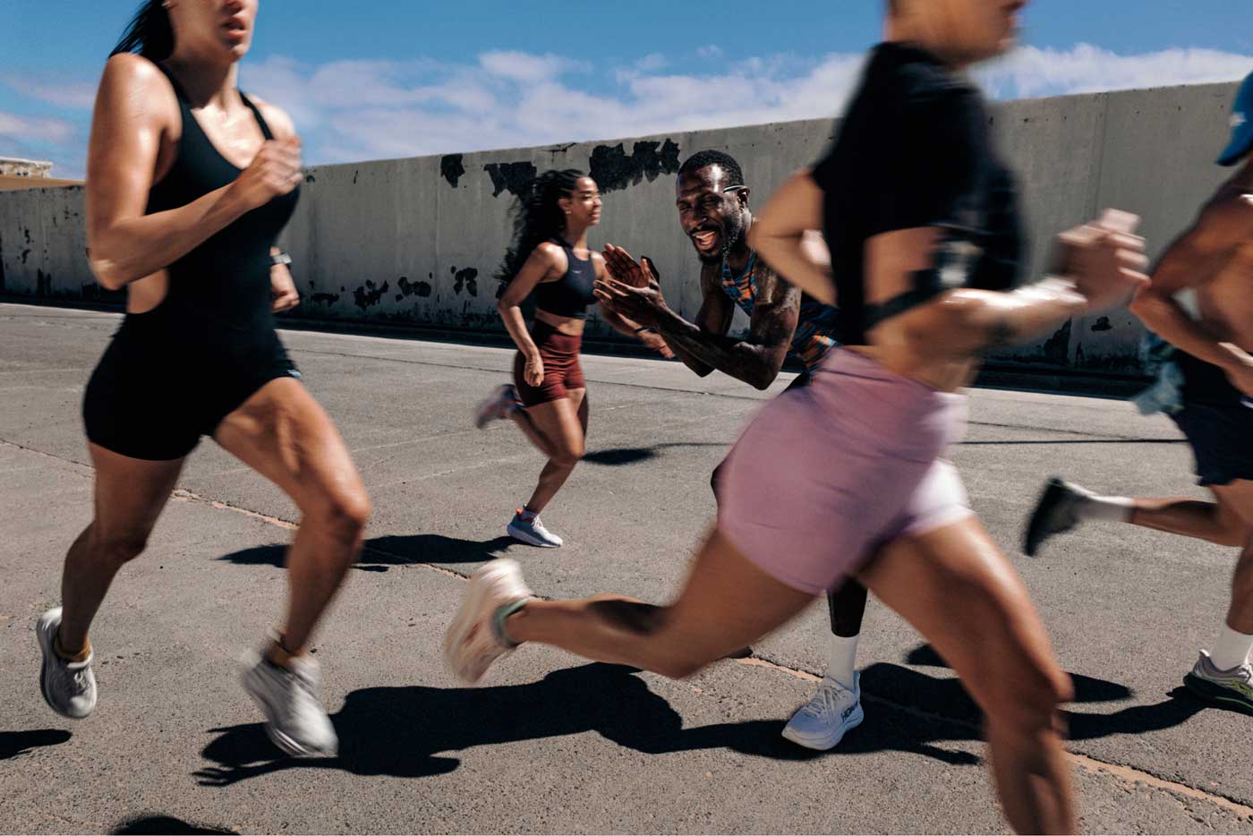Des coureurs en tenue HOKA, courant sur la route alors qu'on les encourage.
