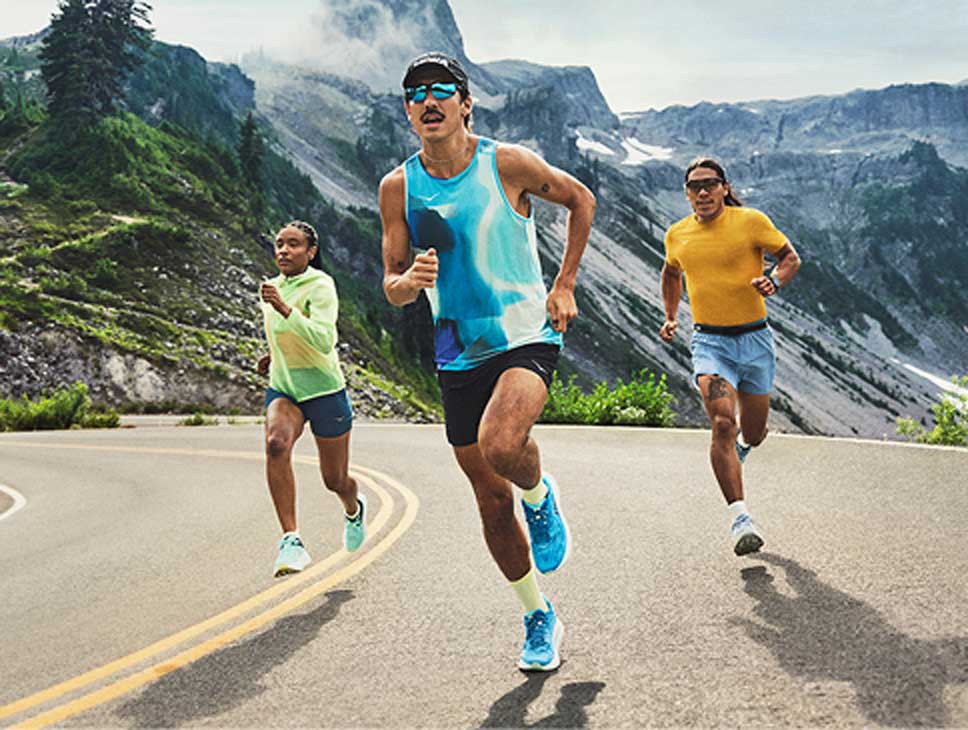 Trois personnes courant sur une route et portant des équipements HOKA.