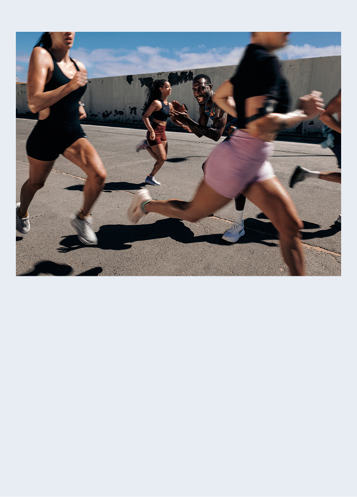 Un groupe diversifié d’athlètes courant vite lors d’une séance d’entraînement en plein air sur une surface asphaltée.