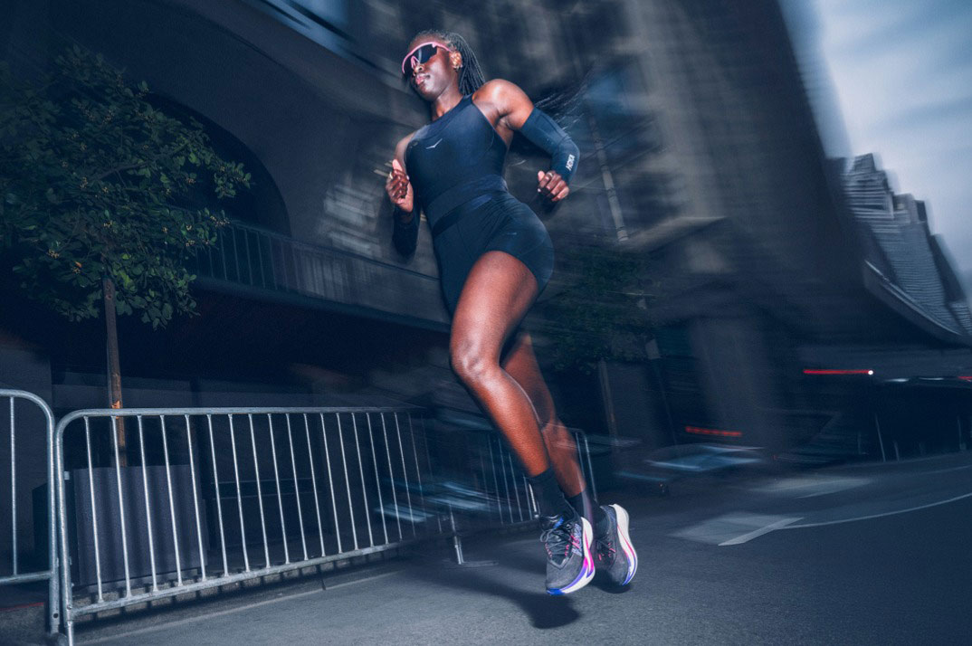 Femme courant sur route dans les rues de la ville en tenue marathon HOKA.