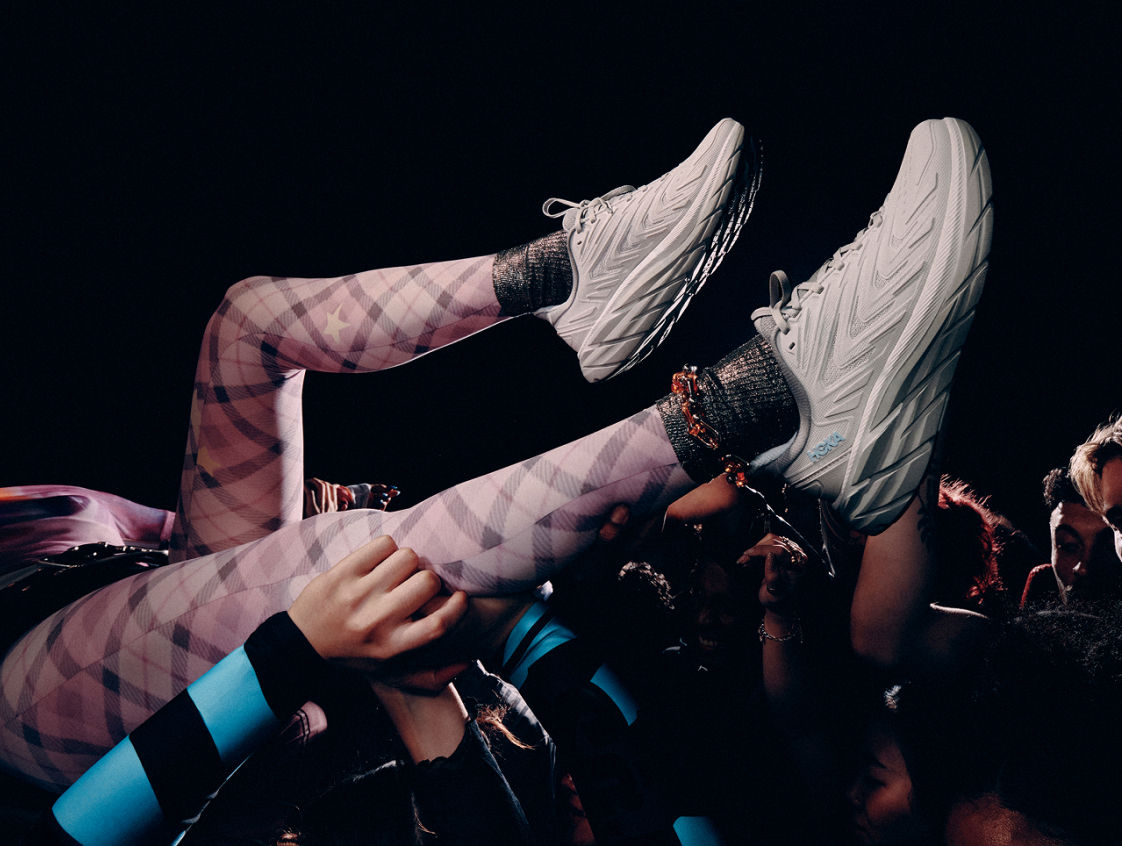 Gros plan d’une personne avec les jambes portant des chaussures HOKA UTL.