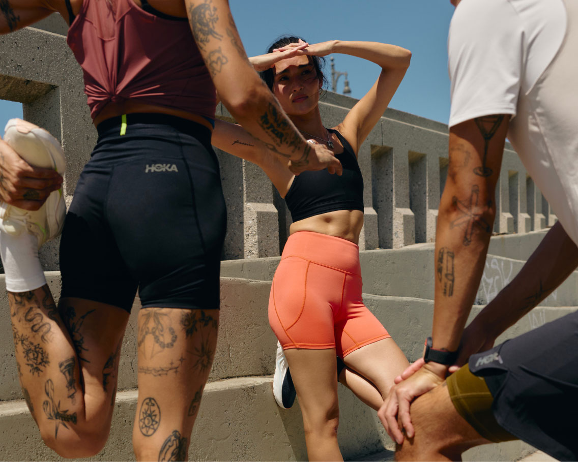 Gros plan de trois personnes debout portant des vêtements HOKA.