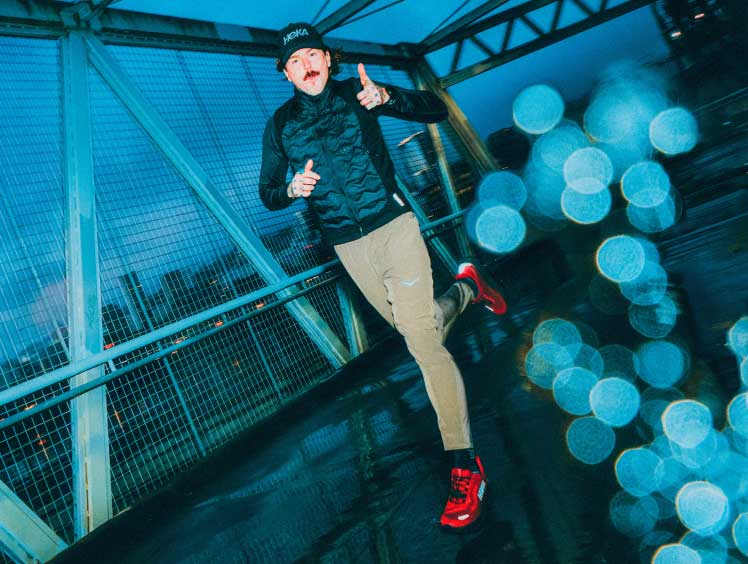 Un homme courant sur un pont sous la pluie tout en portant la Clifton 11 GTX.