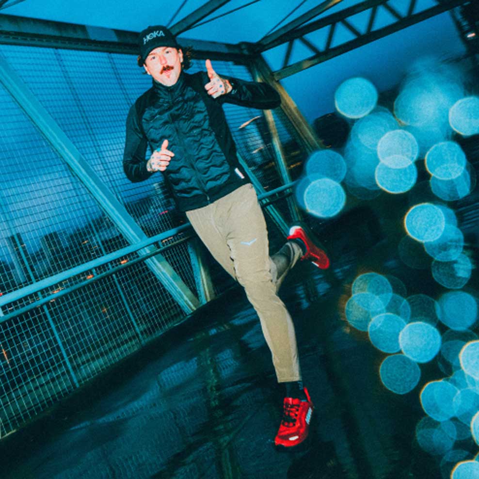 Un homme courant sur un pont sous la pluie tout en portant la Clifton 11 GTX.