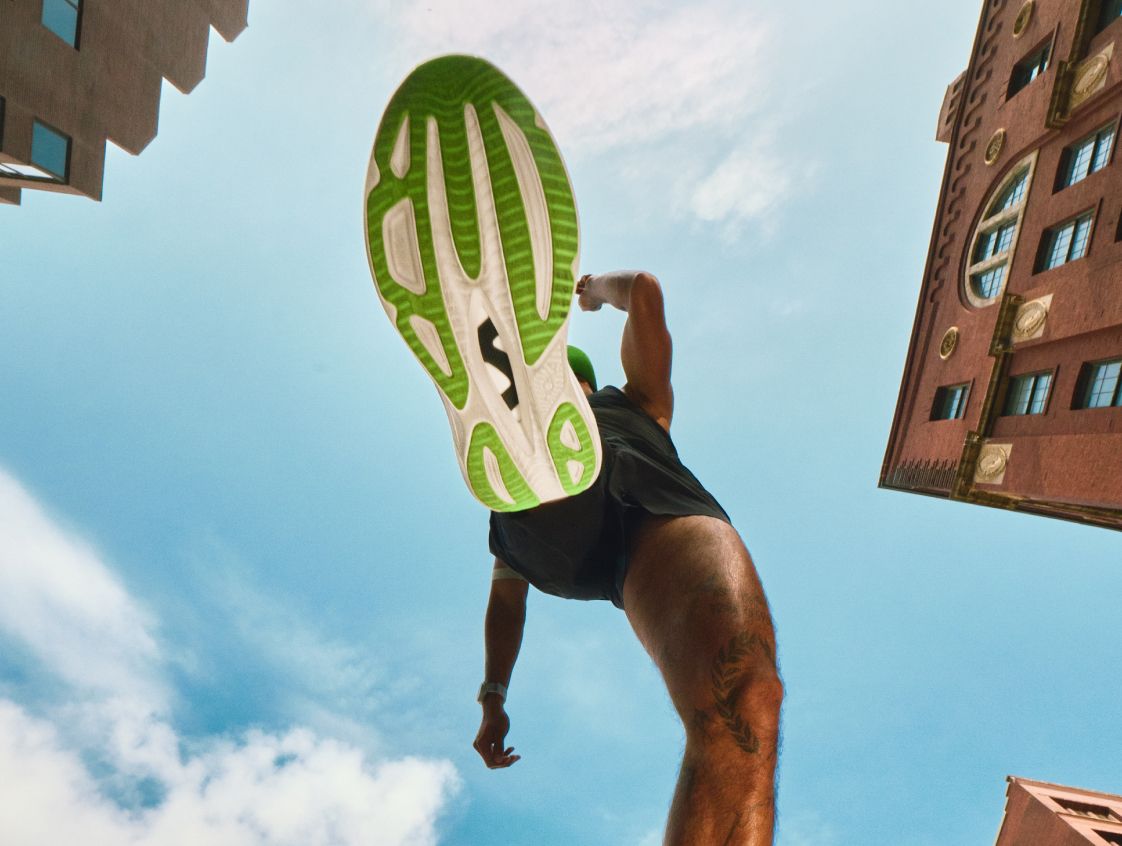 Plan rapproché montrant la semelle extérieure à motifs verts et blancs d’une chaussure de course HOKA.