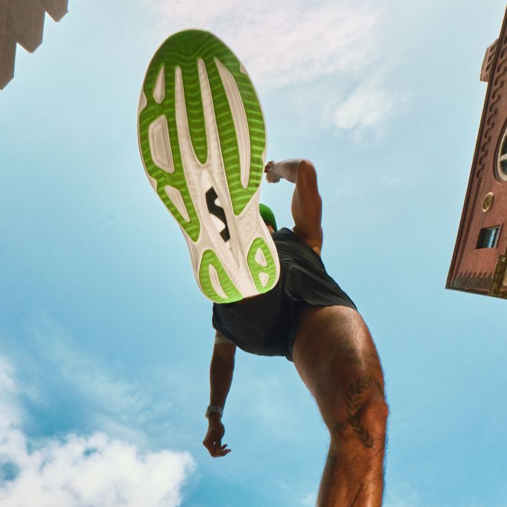 Plan rapproché montrant la semelle extérieure à motifs verts et blancs d’une chaussure de course HOKA.