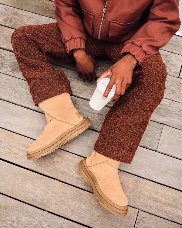 A man sitting on a wooden floor wearing the Classic Distort Boot